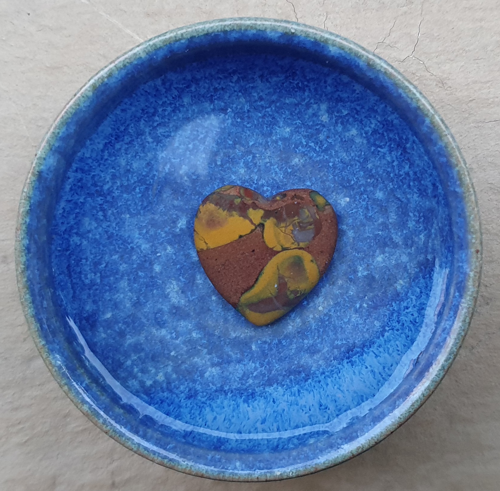 Ein Stein aus Arizona in Herzform, unter Wasser in einer blauen Keramikschale